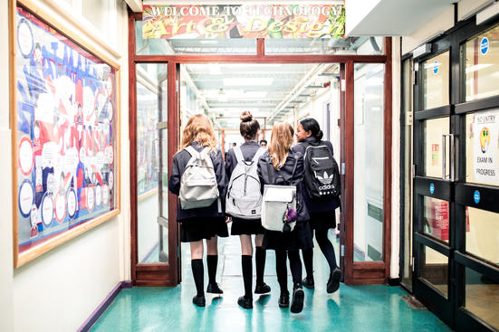 Four pupils walking down a school corridor, backs to the camera