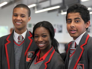 three students in uniform smiling at camera