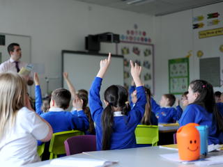 Classroom with pupils raising their hands