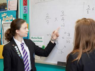 A pupil points at a maths sum on the board