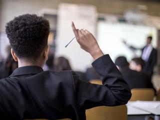 School pupil raising their hand in a classroom