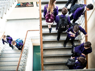 Pupils crossing paths and chatting on a school staircase.