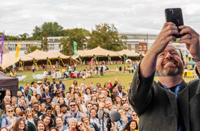 Teach First CEO Russell Hobby on stage taking a selfie of himself and a crowd of spectators