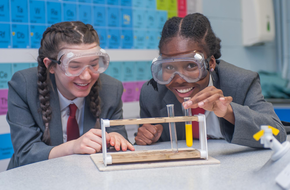 Students with goggles in science class smiling 