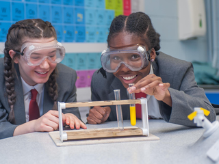 Students with goggles in science class smiling 