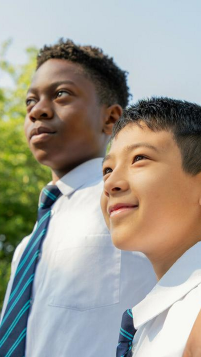 Two male students arm in arm looking upwards