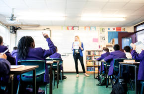 Image of teacher stood at front of classroom facing pupils sat at desks