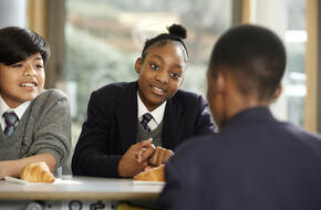 Students in school uniform talking during a lesson.