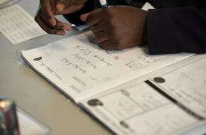 Student working on maths problems in a notebook.